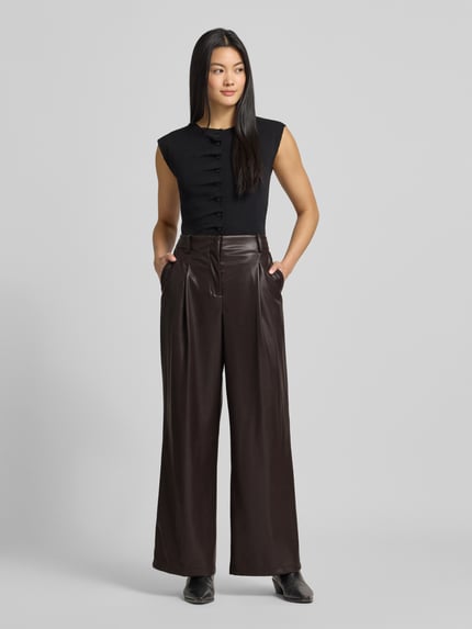 Vrouwenmodel draagt Stoffhose in Leder-Optik van Bash, rechte pasvorm, Franse steekzakken, leren look, volledig frontaal zicht.