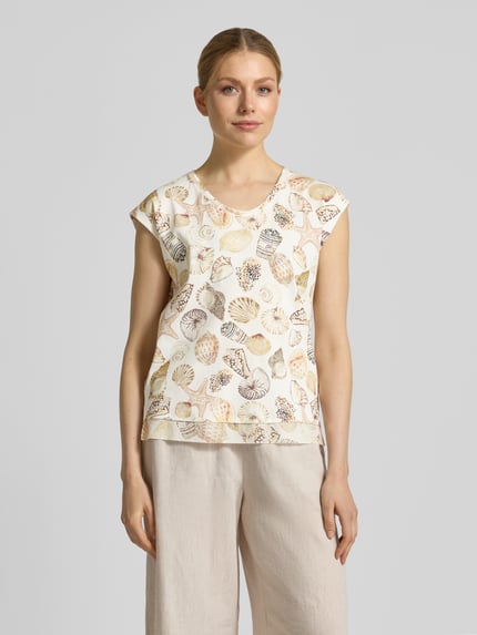 Frauenmodel trägt Regular Fit T-Shirt mit Allover-Motiv-Print von Marc Cain, elastischer Baumwoll-Mix, Rundhalsausschnitt, sanfte Naturfarben, Ganzkörperansicht von vorne.