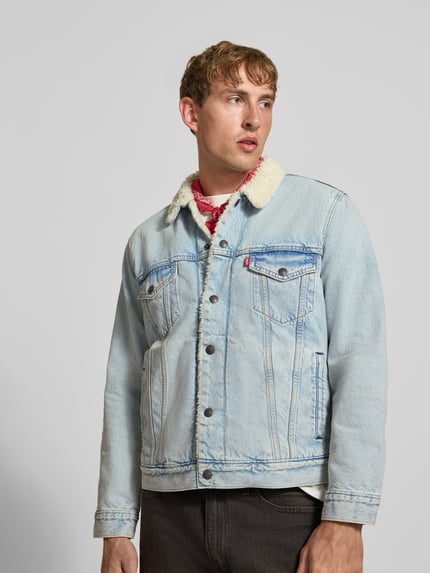 Männermodel trägt Jeansjacke mit Teddykragen von Levi's®, hellblaues Denim, Label-Patch, Knopfleiste, Umlegekragen, Brusttasche, Nahaufnahme Oberkörper.