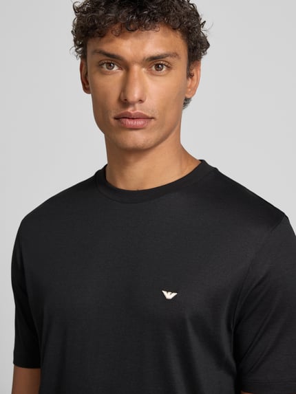 Männermodel trägt T-Shirt mit Label-Stitching von Emporio Armani, schwarz, Lyocell-Baumwoll-Mix, Regular-Fit, Nahaufnahme Oberkörper.