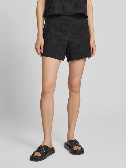 Frauenmodel trägt Regular Fit Stoffshorts aus reiner Baumwolle Modell 'PCGINGER' von PIECES in Schwarz mit dezentem Muster, Nahaufnahme Oberkörper. Damen Stoffshorts von PIECES.