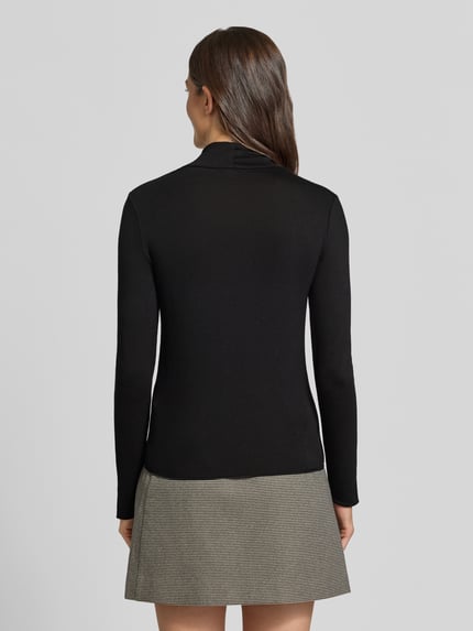 Frauenmodel trägt Longsleeve mit Rollkragen von someday, schwarz, eng anliegend, Ripp-Struktur, Rückenlänge 57 cm, Ganzkörperansicht Rückansicht.
