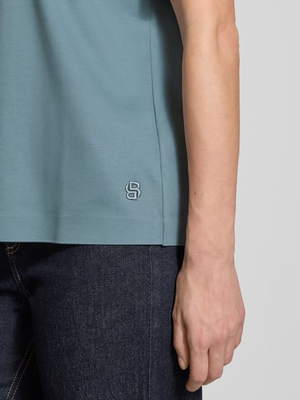 Männermodel trägt Relaxed Fit T-Shirt aus reiner Baumwolle Modell 'EHARPA' von BOSS, jednolita optyka, label stitching, krótki rękaw, niebieski kolor, bawełna, rond dekolt, całkowite zbliżenie dolnej części torsu