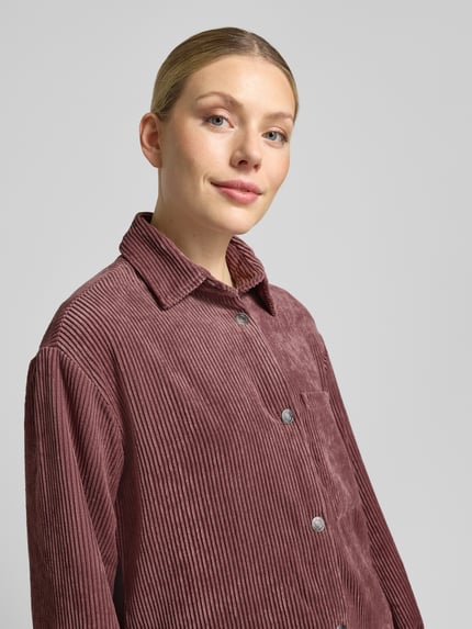 Frauenmodel trägt Regular Fit Hemdbluse aus Cord Modell 'La44ni' von ZABAIONE, Knopfleiste, Brusttasche, rosefarben, Nahaufnahme Oberkörper.