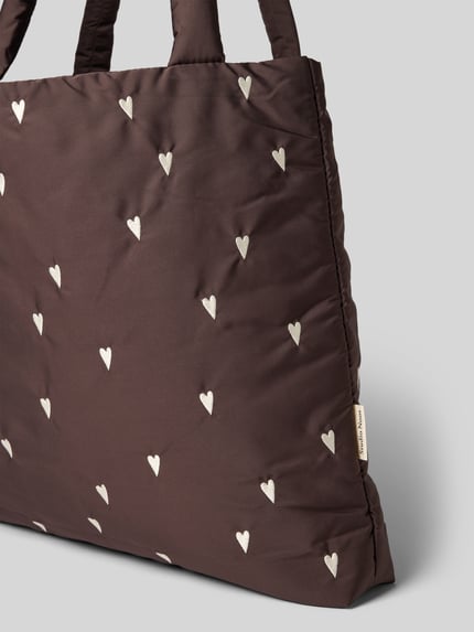Produktfoto, Tote Bag mit Logo-Detail Modell 'Puffy' von Studio Noos, brauner Stoff mit weißen Herz-Stickereien, strukturierte Oberfläche.