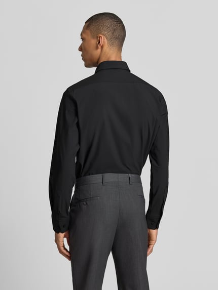 Männermodel trägt Regular Fit Businesshemd mit Kentkragen Modell 'JOE' von BOSS, Optik: Unifarben, Ganzkörperansicht Rückansicht. Passform: Regular-Fit, Knopfleiste: durchgehend, Ärmelabschluss: Manschette, Materialverarbeitung: Performance-Stretch-Jersey, Applikation: Label-Applikation.