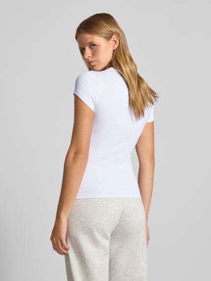 Frauenmodel trägt Skinny Fit T-Shirt aus Baumwoll-Mix von Gina Tricot in Weiß, kurzärmlig, glatte Textur, Rückenansicht, Ganzkörperansicht Rückansicht.