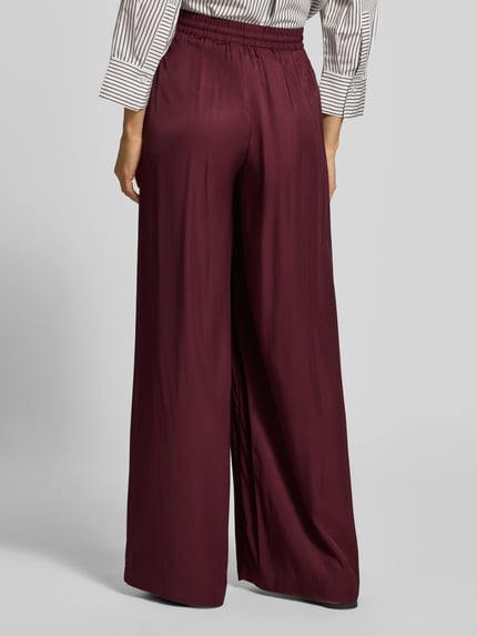 Frauenmodel trägt Weite Hose mit Tunnelzug von BOSS Orange, unifarbenes Design, elastischer Bund, gerippter Beinabschluss, Ganzkörperansicht Rückansicht