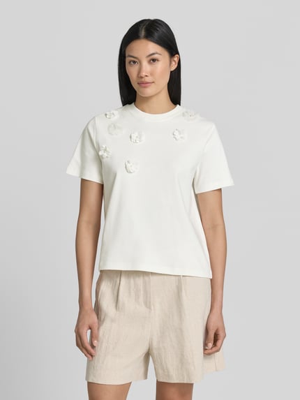 Frauenmodel trägt T-Shirt mit floralen Applikationen von Christian Berg Woman, Reine Baumwolle, Gerader-Schnitt, Rundhalsausschnitt, 1/2-Arm, Rückenlänge bei Größe S: 52 cm, helle Farben und glatte Textur, Ganzkörperansicht von vorne.