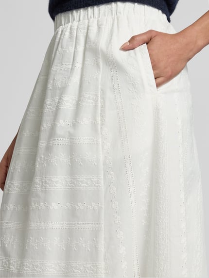Vrouwenmodel draagt maxirok met stitchings en elastische band van Lanius, puur katoen, a-lijn, detailopname heup en band.