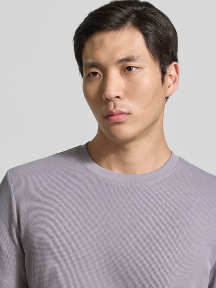 Männermodel trägt Regular Fit T-Shirt aus Baumwoll-Mix von Tom Tailor Denim, Optik: Unifarben, Piqué Textur, Rundhals, Nahaufnahme Oberkörper.