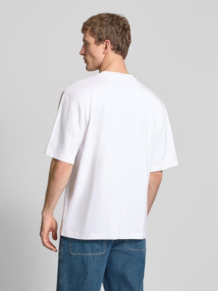 Männermodel trägt weißes Oversized T-Shirt mit Logo und Rundhalsausschnitt von The North Face aus reiner Baumwolle, Rückenlänge 73 cm, Ganzkörperansicht Rückansicht.