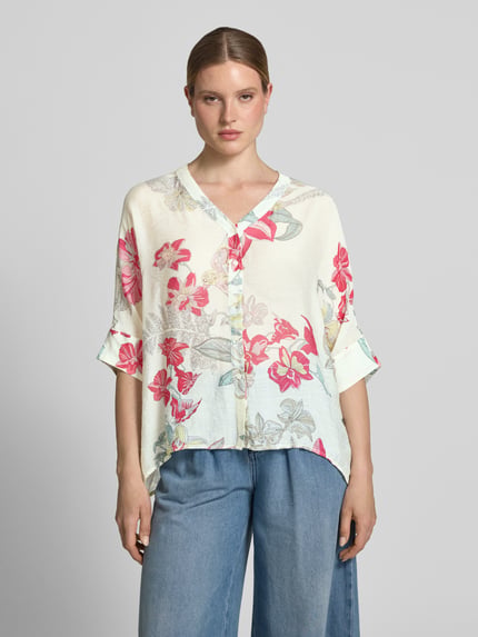 Frauenmodel trägt Relaxed Fit Bluse aus Viskose-Mix im Allover-Look von Comma in Creme mit floralen Mustern, Knopfleiste, V-Ausschnitt, 3/4-Arm, verlängertem Rückenteil, Ganzkörperansicht von vorne.