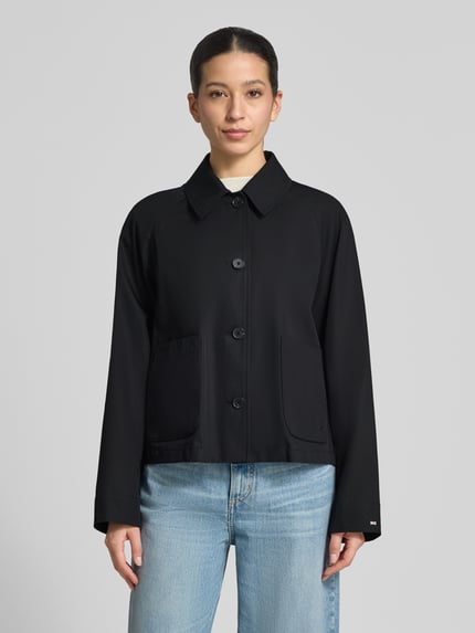 Frauenmodel trägt Relaxed Fit Trenchcoat aus reiner Baumwolle von Tommy Hilfiger in Optik: Unifarben, wasserabweisend, Twill, Logo-Detail, Cropped, Knopfleiste, Ärmelabschluss gerade, Ganzkörperansicht von vorne.