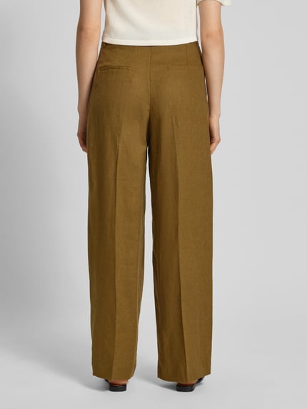 Frauenmodel trägt Straight Fit Leinenhose mit Bügelfalten Modell 'Tempoli' von Mango in olivgrün, reine Leinen, Ganzkörperansicht Rückansicht.