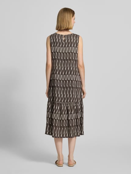 Frauenmodel trägt Midikleid mit rückseitigem Schlüsselloch-Ausschnitt von OPUS, Reine Viskose, Gerader-Schnitt, Modell 'Wicy bamboo', Rückenlänge 115 cm, Brustweite 49 cm, braunes und weißes Muster, fließende Textur, Ganzkörperansicht Rückansicht.