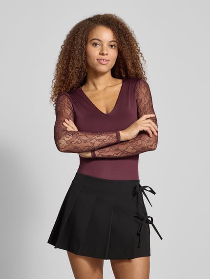 Frauenmodel trägt Slim Fit Body mit Spitzenärmeln Modell 'SIA' von Only in unifarbener, semitransparenter Optik mit Stretch-Webstruktur, V-Ausschnitt, Langarm, Spitze, Druckknopfverschluss; Nahaufnahme Oberkörper.