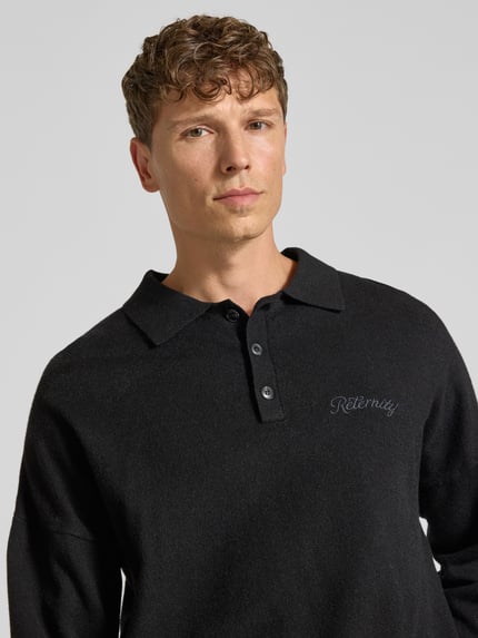 Männermodel trägt gebreide pullover met polokraag en knoopsluiting van RETERNITY, Materiaalmix met katoen, regular fit, labelstitching, ruglengte maat M 65 cm, mouwlengte maat M 48 cm, kleur zwart, zachte textuur, nahaufnahme bovenlichaam