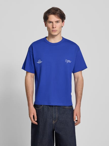 Männermodel trägt Regular Fit T-Shirt mit überschnittenen Schultern von JACK & JONES, Herren T-Shirt aus Baumwoll-Mix in Blau, Rundhalsausschnitt, Ganzkörperansicht von vorne. Rückenlänge bei Größe M: 66 cm, Statement-Print auf der Rückseite.