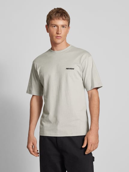 Männermodel trägt Relaxed Fit T-Shirt aus reiner Baumwolle von REVIEW, graue Farbe, Logo-Stickerei, kurzärmelig, Ganzkörperansicht von vorne.
