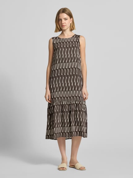 Frauenmodel trägt Midikleid mit rückseitigem Schlüsselloch-Ausschnitt von OPUS aus reiner Viskose im geraden Schnitt, braun mit weißem Bambusmuster, Rundhalsausschnitt, Modell 'Wicy bamboo', Ganzkörperansicht von vorne.