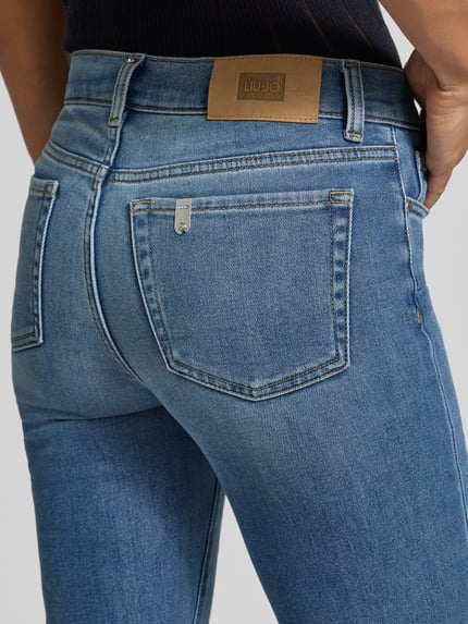 Frauenmodel trägt Flared Jeans mit Eingrifftaschen von Liu Jo White, blauer Baumwoll-Mix, Used-Look, Nahaufnahme Rückansicht.