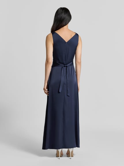 Frauenmodel trägt Abendkleid mit Wasserfallausschnitt von Rinascimento in Dunkelblau, Material-Mix mit Stretch-Anteil, taillierte Passform, geraffter Stoffgürtel, Rückansicht, Ganzkörperansicht Rückansicht.