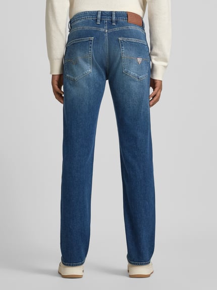 Männermodel trägt Slim Fit Jeansy im Used-Look Modell 'ANGELS' od Guess z bawełny, wpuszczane kieszenie, efekt znoszenia, widok z tyłu, Ganzkörperansicht Rückansicht.
