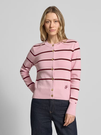 Frauenmodel trägt Regular Fit Strickjacke aus reiner Baumwolle von Tommy Hilfiger in Rosa mit braunen Streifen, Feinstrick, Logo-Stitching, Rundhals, gerippte Abschlüsse, einreihige Knopfleiste, Ganzkörperansicht von vorne.