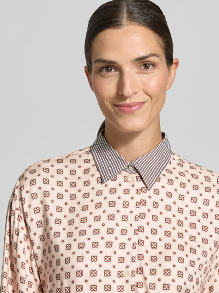 Vrouwenmodel draagt Regular Fit Hemdbluse aus reiner Viskose mit Allover-Muster van Emily Van den Bergh, zachte kleuren, fijne print, blousekraag, detailopname bovenlichaam.