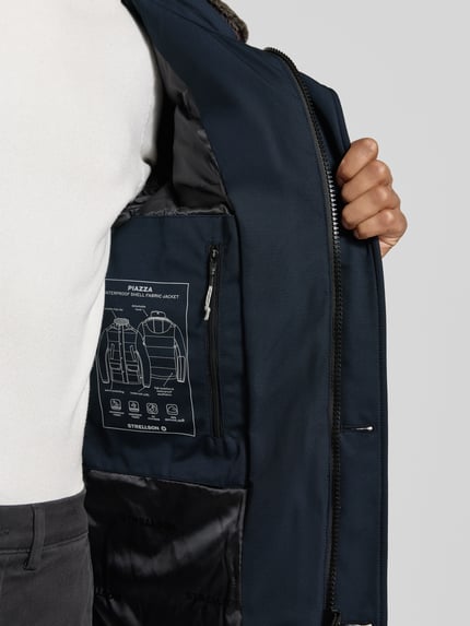 Męski model nosi Steppjacke mit Kapuze Modell 'PIAZZA' od Strellson, granatowy kolor, patki, zamek, guziki, kaptur, widok z przodu, zbliżenie na wnętrze kurtki.