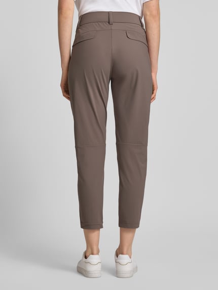 Frauenmodel trägt Stoffhose in 7/8-Länge mit Stretch-Anteil Modell 'NATINA' von Raffaello Rossi, Elastischer-Material-Mix, körpernahe Passform, Elastikbund mit Gürtelschlaufen, Reißverschlusstaschen, Farbe Braun, glatte Textur, Ganzkörperansicht Rückansicht.
