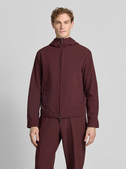 Männermodel trägt Jacke mit Kapuze und Zweiwege-Reißverschluss von Emporio Armani in Burgunderrot, Material-Mix mit Stretch-Anteil, Eingrifftaschen, Regular-Fit, Ganzkörperansicht von vorne. Rückenlänge 66 cm, Schulterbreite 56 cm, Brustweite 58 cm, Ärmellänge 68 cm bei Größe 50.