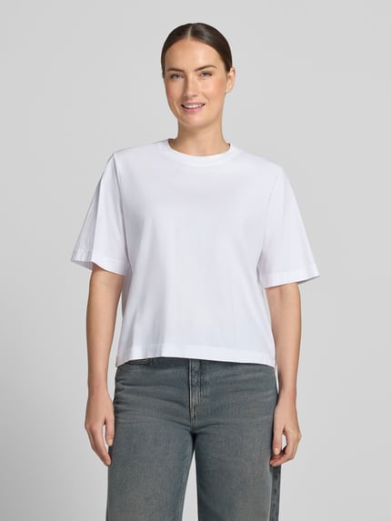 Frauenmodel trägt Oversized Fit T-Shirt aus reiner Baumwolle von DRYKORN, weiß, Rundhalsausschnitt, Halbarm, Ganzkörperansicht von vorne.