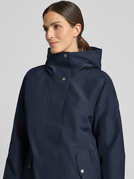 Frauenmodel trägt Regular Fit Parka mit Kapuze Modell 'Alana' von Didriksons, dunkelblau, glatte Textur, Eingrifftaschen, Nahaufnahme Oberkörper, Rückenlänge 90 cm, Schulterbreite 38 cm, Brustweite 48 cm, Ärmellänge 74 cm