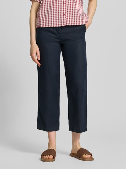 Frauenmodel trägt Leinenhose in verkürzter Passform von Christian Berg Woman, dunkelblau, mit Eingrifftaschen und Paspeltaschen, Reines Leinen, Ganzkörperansicht von vorne.