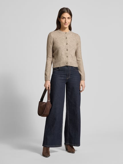 Frauenmodel trägt Regular Fit Cardigan mit Woll-Anteil Modell 'Nekka' von Mango, beige, Rundhalsausschnitt, Knopfleiste, Ganzkörperansicht von vorne.