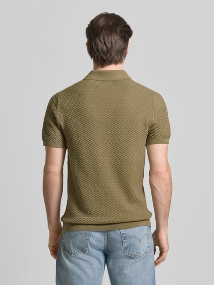 Męski model nosi koszulkę polo z kołnierzykiem polo i dekoltem w serek z czystej bawełny, krój body fit, od JAKE*S STUDIO MEN, długość tyłu w rozmiarze M: 73 cm, długość rękawów w rozmiarze M: 25 cm, widok całej sylwetki od tyłu.