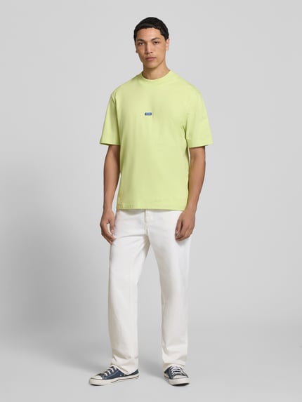 Męski model nosi Regular Fit T-Shirt aus reiner Baumwolle Modell 'NIEROS' von Hugo Blue, jednokolorowe, krój regular fit, krótki rękaw, okrągły dekolt, logo detail, bawełna, jasny żółty, Ganzkörperansicht von vorne.