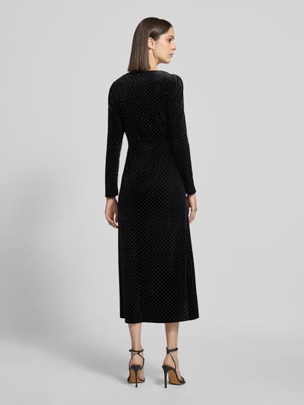 Frauenmodel trägt Cocktailkleid im Allover-Look Modell 'HELLA' von YAS, schwarz mit Punktmuster, figurbetont, Ganzkörperansicht Rückansicht.