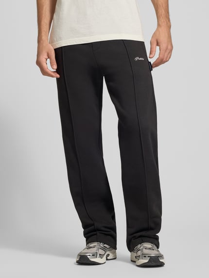 Männermodel trägt schwarze Sweatpants mit elastischem Bund und Label-Stitching von PROHIBITED, Baumwoll-Mix, Loose Fit, Nahaufnahme Unterkörper.