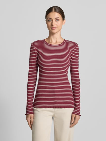 Frauenmodel trägt Slim Fit Langarmshirt aus Baumwoll-Mix Modell 'ANNA' von Selected, rot mit weißen Streifen, Ganzkörperansicht von vorne.