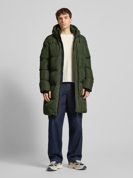 Mannelijk model draagt Steppmantel met Kapuze und Zweiwege-Reißverschluss van Superdry, olijfgroen met rechte snit, zijzakken, elastische mouwuiteinden, voooraanzicht hele lichaam.