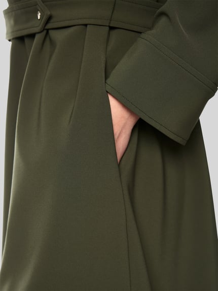 Frauenmodel trägt Knielanges Kleid mit Stehkragen und Gürtel von Marc Cain in Olivgrün, feine Struktur, Material-Mix, Detailaufnahme.