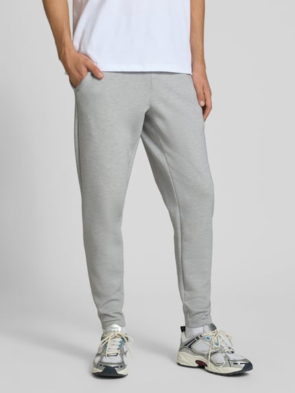 Mężczyznamodel nosi Regular Fit Sweatpants mit Lyocell-Anteil von PUMA PERFORMANCE w jasnoszarym odcieniu, elastyczna mieszanka materiałów, detal z logo, elastyczny pas z tunelem, elastyczne zakończenia nogawek, Długość wewnętrzna nogawki w rozmiarze M: 76 cm, Ganzkörperansicht z przodu.