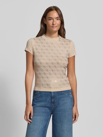 Frauenmodel trägt T-Shirt im Allover-Look mit Ziersteinbesatz von GUESS, Beige mit Muster, Slim Fit, Baumwoll-Elasthan, Nahaufnahme Oberkörper.