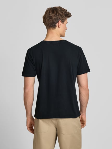 Männermodel trägt T-Shirt aus Baumwoll-Leinen-Mix mit V-Ausschnitt von Superdry in Schwarz, Regular-Fit, feines Stitching, Rückenlänge 68 cm bei Größe M, Ganzkörperansicht Rückansicht.
