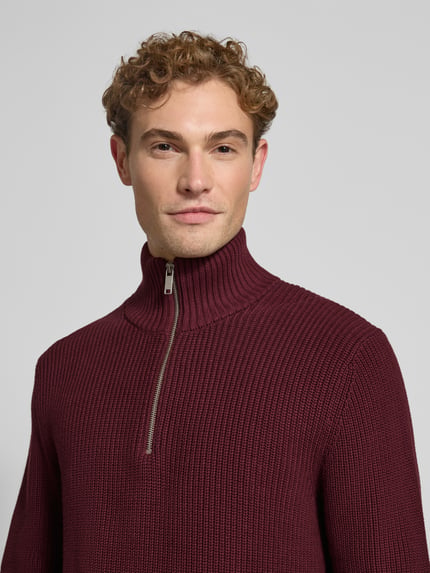 Männermodel trägt Slim Fit Strickpullover aus reiner Baumwolle mit Troyer-Kragen von MCNEAL in Weinrot, Nahaufnahme Oberkörper, gerippte Abschlüsse, langärmliges Design, Rückenlänge 72 cm, Ärmellänge 74 cm.
