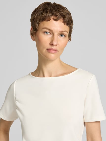 Frauenmodel trägt T-Shirt in asymmetrischer Form Modell 'Helle' von My Essential Wardrobe in Creme, Material-Mix mit Viskose, Nahaufnahme Oberkörper.