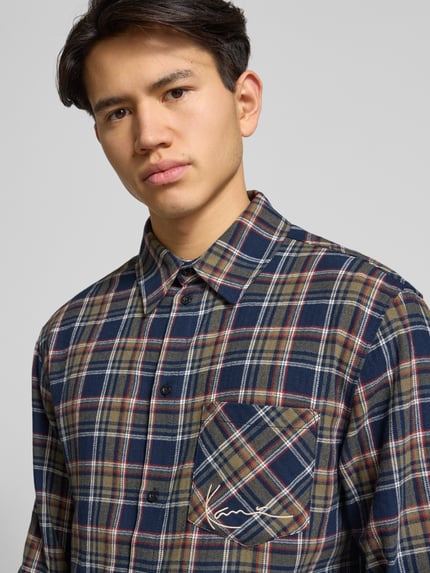 Männermodel trägt Freizeithemd mit Knopfleiste von KARL KANI aus reiner Baumwolle, Regular Fit, kariertes Muster, Nahaufnahme Oberkörper.